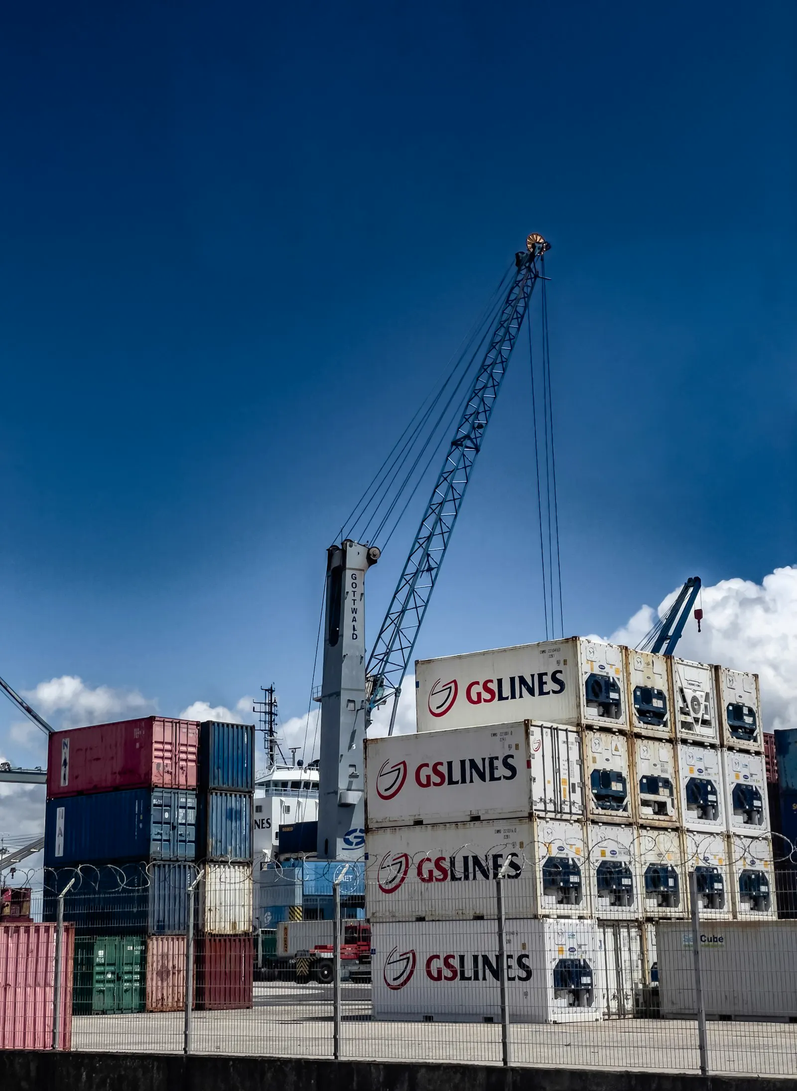 Refrigerated containers stacked at a port under a crane